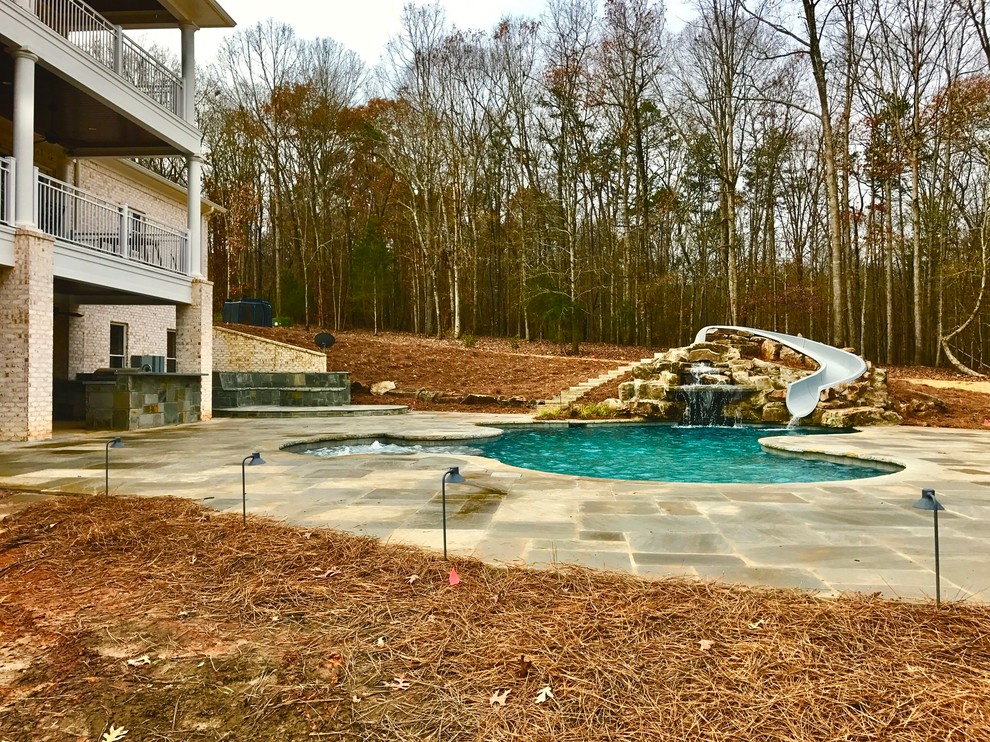 Esempio di una grande piscina classica personalizzata dietro casa con un acquascivolo e pavimentazioni in cemento