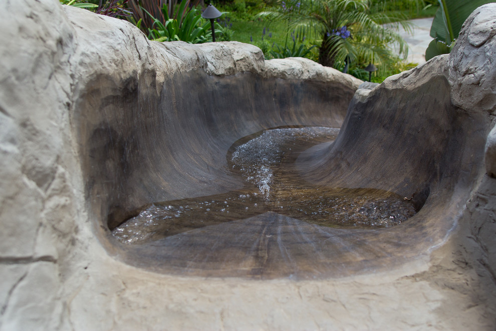 Exemple d'une grande piscine naturelle et arrière craftsman sur mesure avec un toboggan et des pavés en pierre naturelle.