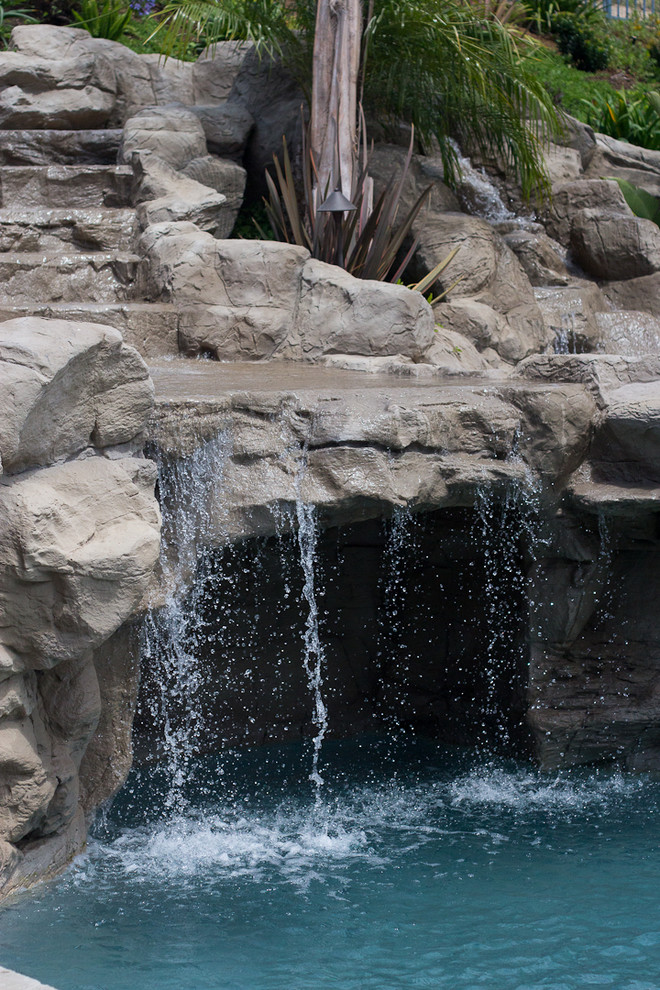 Cette photo montre une grande piscine naturelle et arrière craftsman sur mesure avec un toboggan et des pavés en pierre naturelle.
