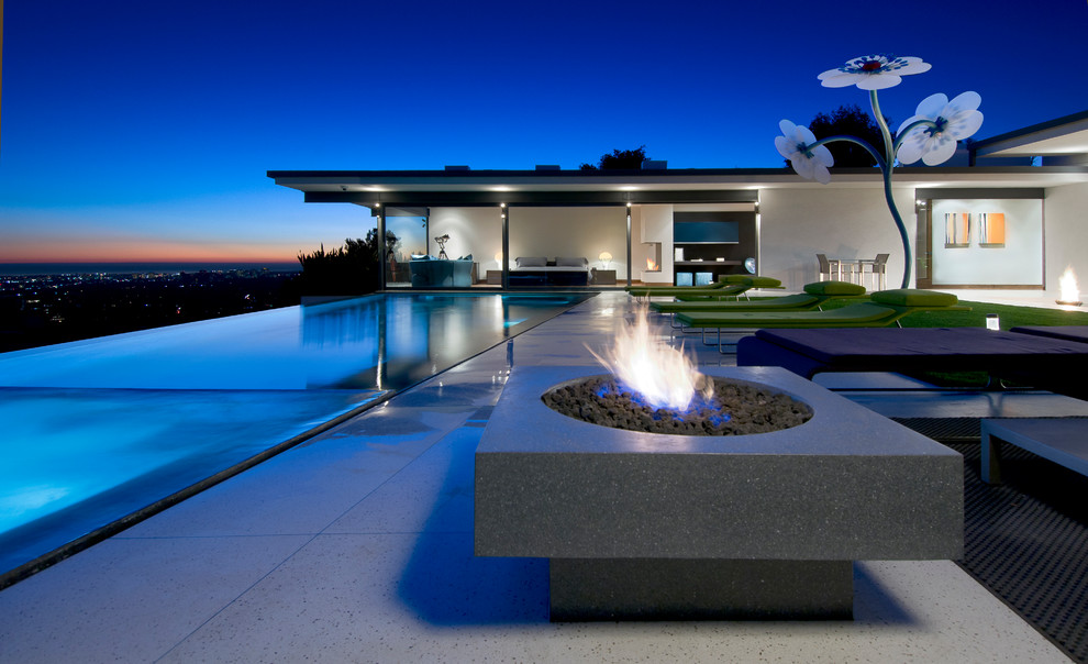 Esempio di un'ampia piscina a sfioro infinito minimalista rettangolare dietro casa con paesaggistica bordo piscina e piastrelle