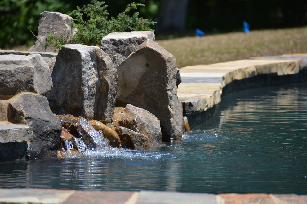 Immagine di una grande piscina monocorsia country personalizzata dietro casa con una vasca idromassaggio e pavimentazioni in cemento