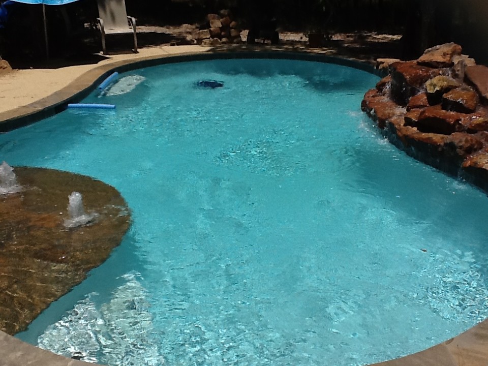 Idee per una piscina rustica personalizzata di medie dimensioni e dietro casa con fontane e lastre di cemento