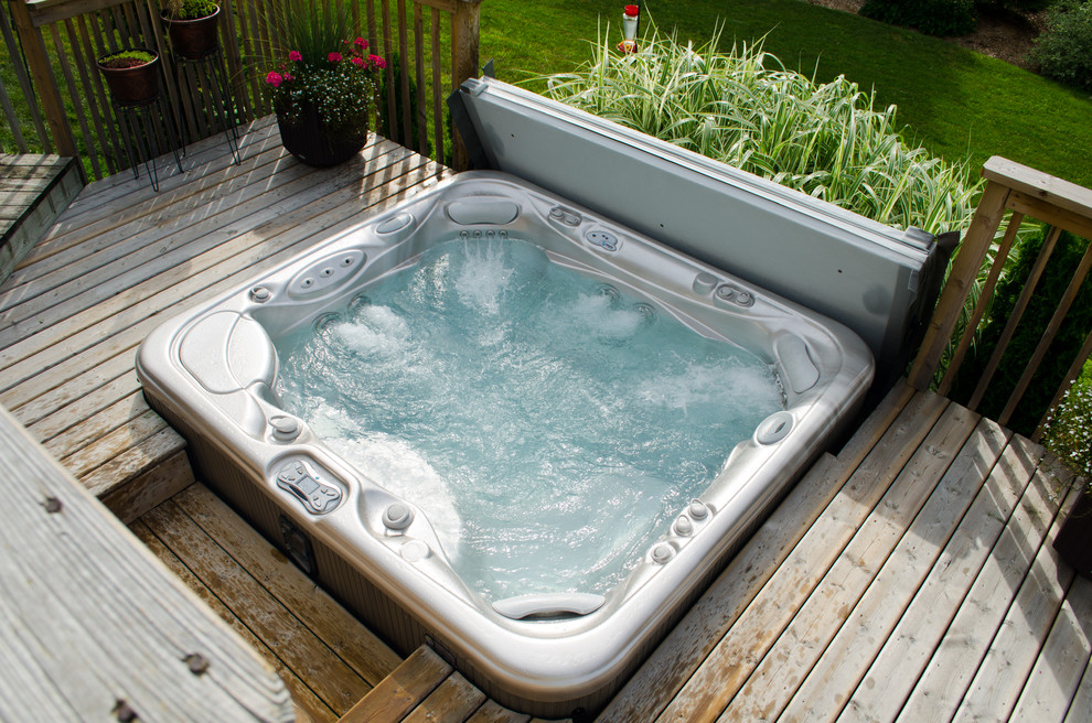 Hot tub - mid-sized traditional backyard custom-shaped aboveground hot tub idea in Other with decking