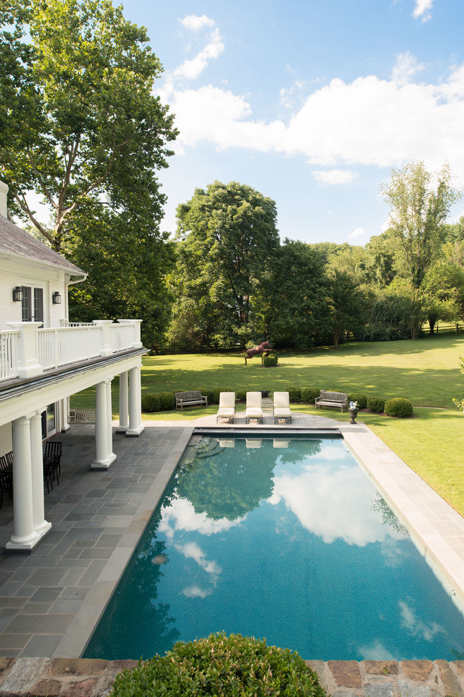 Modelo de piscina con fuente clásica rectangular en patio trasero con adoquines de piedra natural