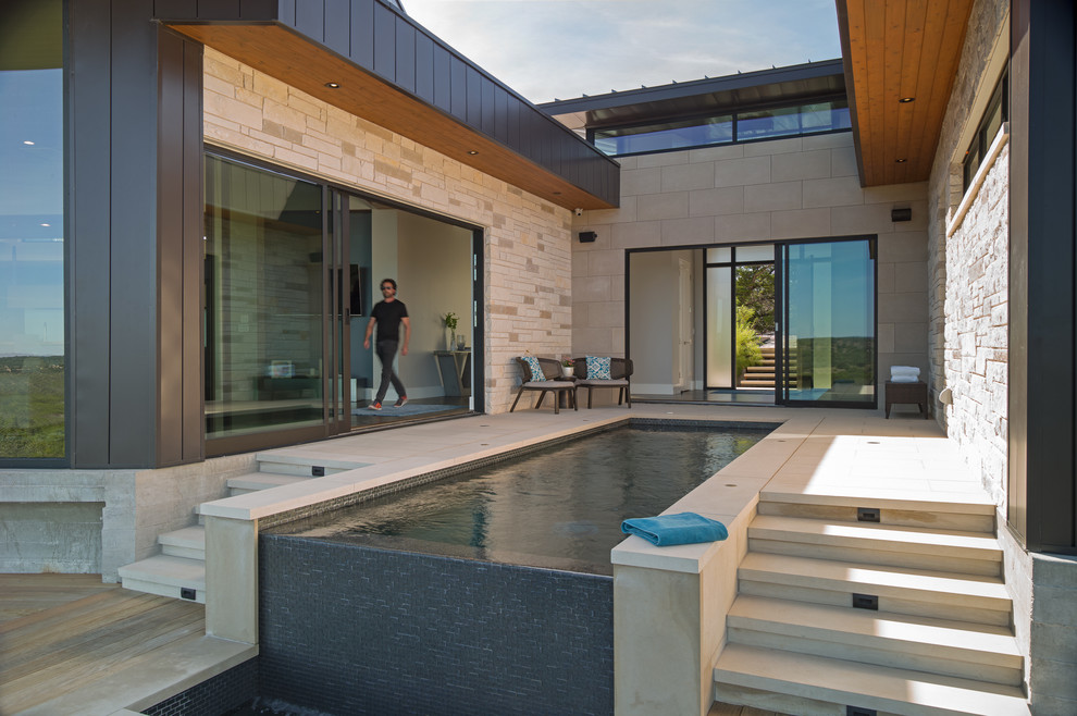 This is an example of a medium sized contemporary courtyard custom shaped infinity swimming pool in Austin with concrete paving.
