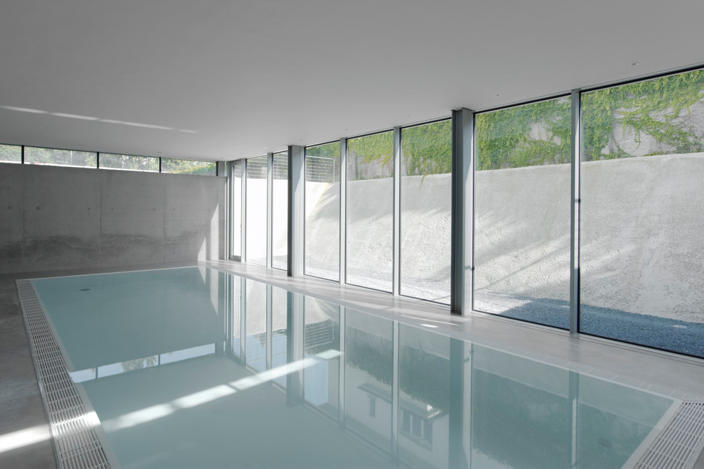 Aménagement d'une grande piscine intérieure contemporaine rectangle avec une dalle de béton.