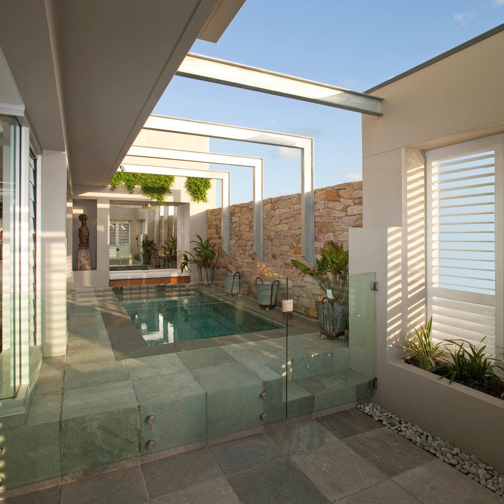 Inspiration for a small contemporary rectangular swimming pool in Sydney with natural stone paving.