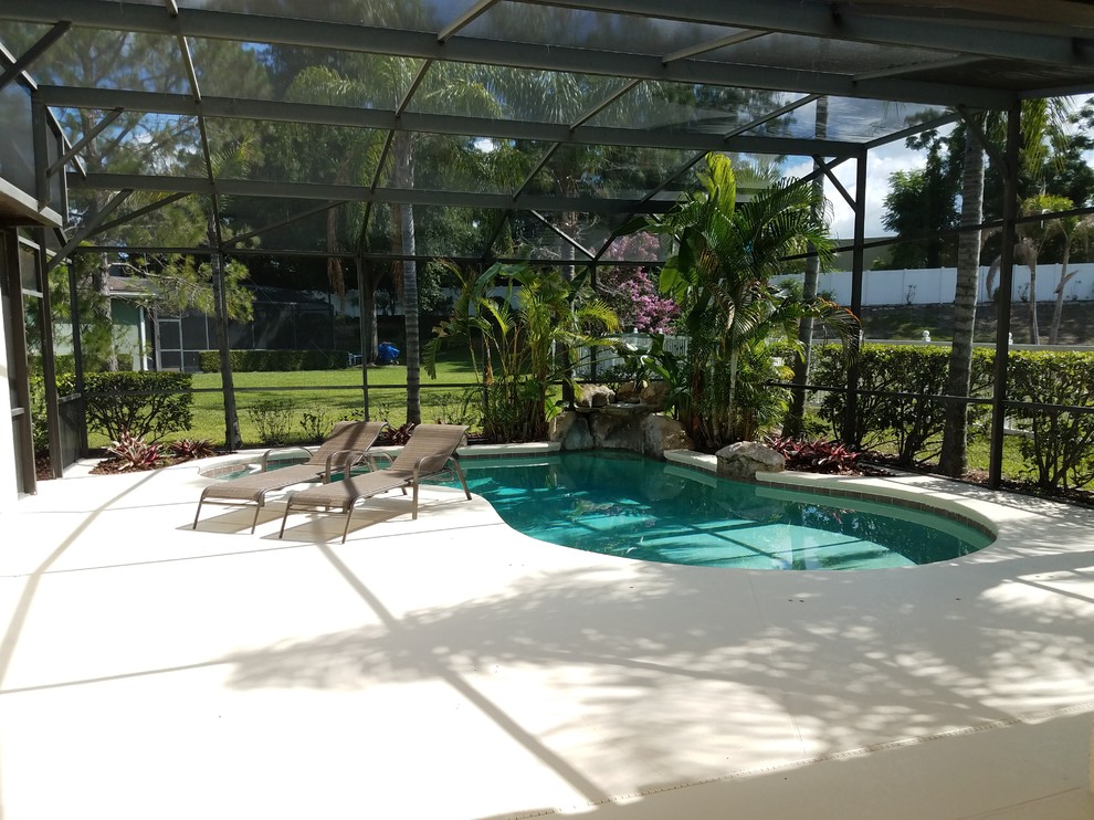 Immagine di una grande piscina monocorsia personalizzata dietro casa con fontane e pavimentazioni in cemento