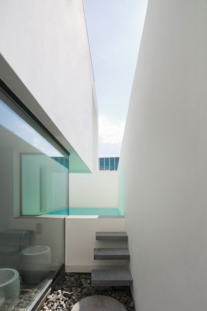 Cette image montre un petit couloir de nage minimaliste rectangle avec une cour et des pavés en béton.