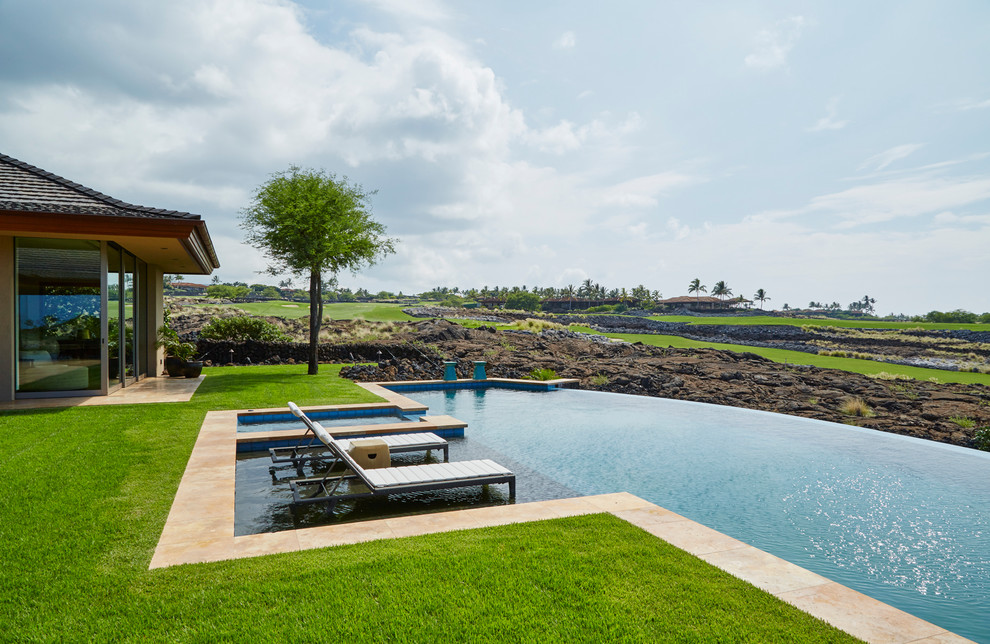 Immagine di una grande piscina a sfioro infinito tropicale personalizzata dietro casa con una vasca idromassaggio e pavimentazioni in pietra naturale