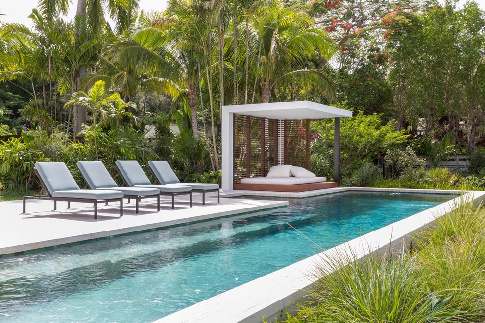 Modelo de piscina alargada tropical rectangular en patio lateral con adoquines de piedra natural