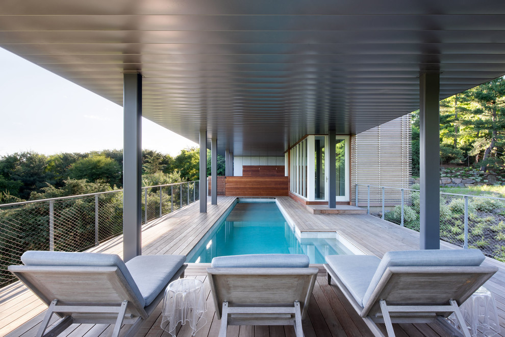 Réalisation d'un couloir de nage design en L avec une terrasse en bois.