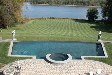 Immagine di una grande piscina a sfioro infinito vittoriana personalizzata dietro casa con una vasca idromassaggio e pavimentazioni in pietra naturale