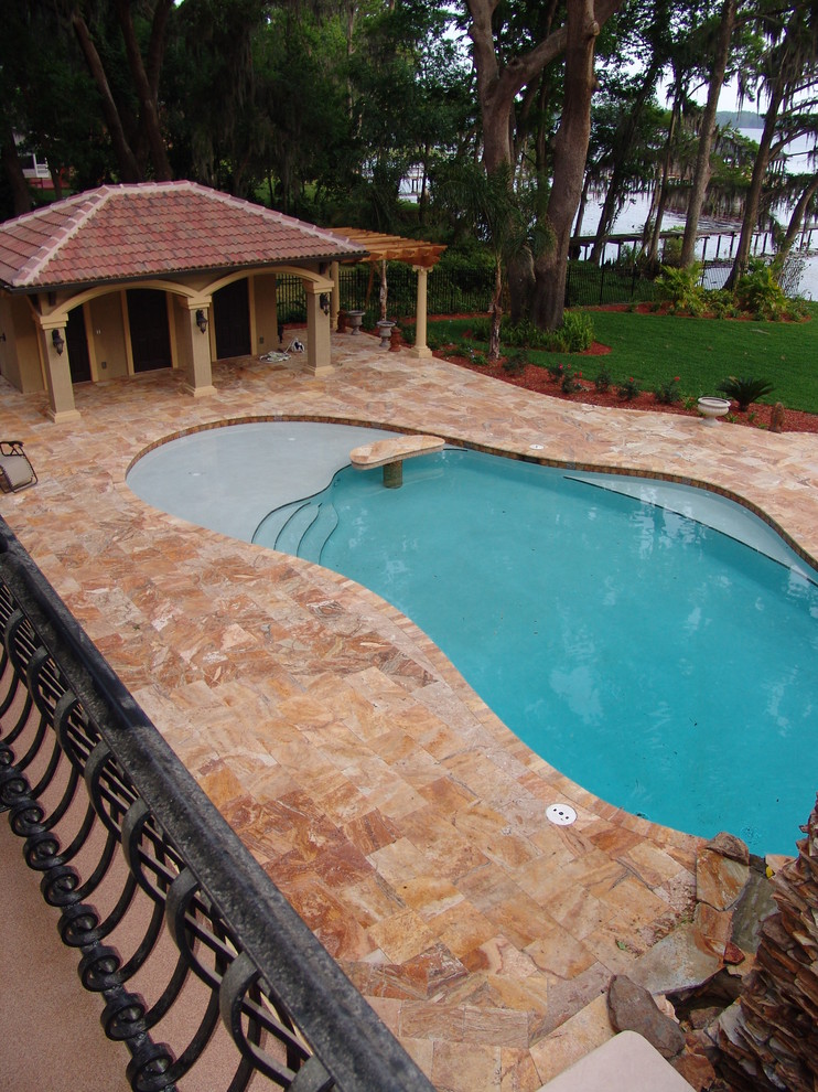 Immagine di una grande piscina monocorsia mediterranea a "C" dietro casa con una dépendance a bordo piscina e piastrelle