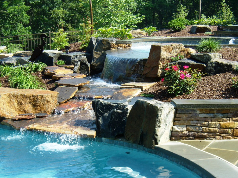Idée de décoration pour une piscine naturelle et arrière tradition sur mesure avec un point d'eau et des pavés en pierre naturelle.
