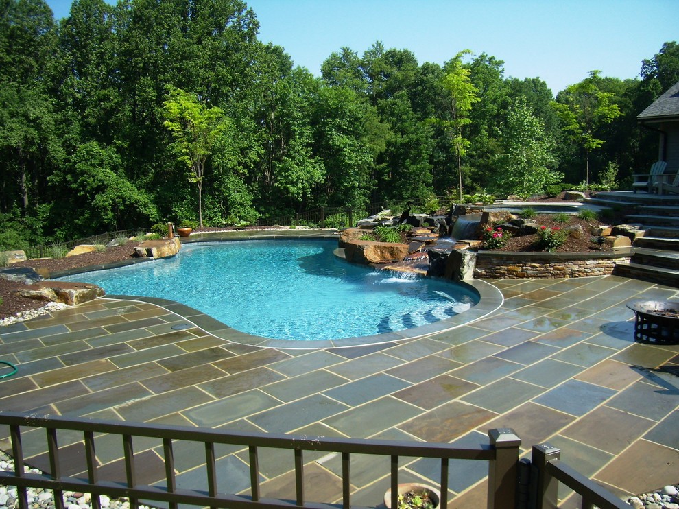 Ejemplo de piscina con fuente natural tradicional a medida en patio trasero con adoquines de piedra natural