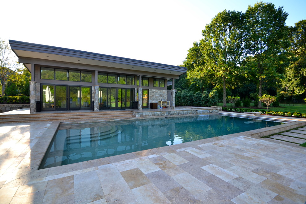 Exempel på en stor modern rektangulär träningspool på baksidan av huset, med poolhus och naturstensplattor