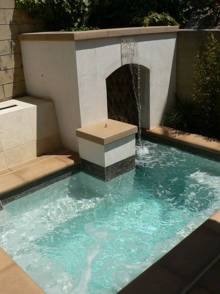 Modelo de piscinas y jacuzzis mediterráneos pequeños a medida en patio trasero con losas de hormigón
