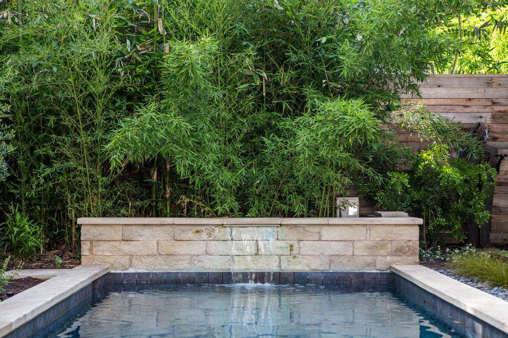 Esempio di una piscina monocorsia minimalista rettangolare di medie dimensioni e dietro casa con fontane e pavimentazioni in pietra naturale