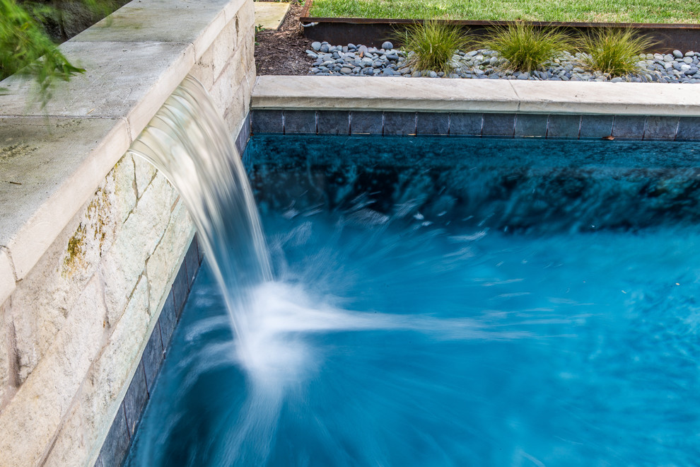 Foto de piscina con fuente alargada minimalista de tamaño medio rectangular en patio trasero con adoquines de piedra natural