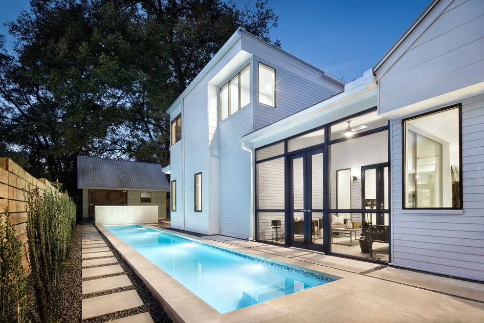 Diseño de piscina alargada actual grande rectangular en patio trasero con adoquines de hormigón