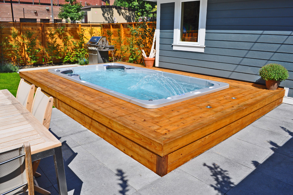 Modelo de piscinas y jacuzzis elevados de estilo americano de tamaño medio rectangulares en patio trasero con adoquines de hormigón