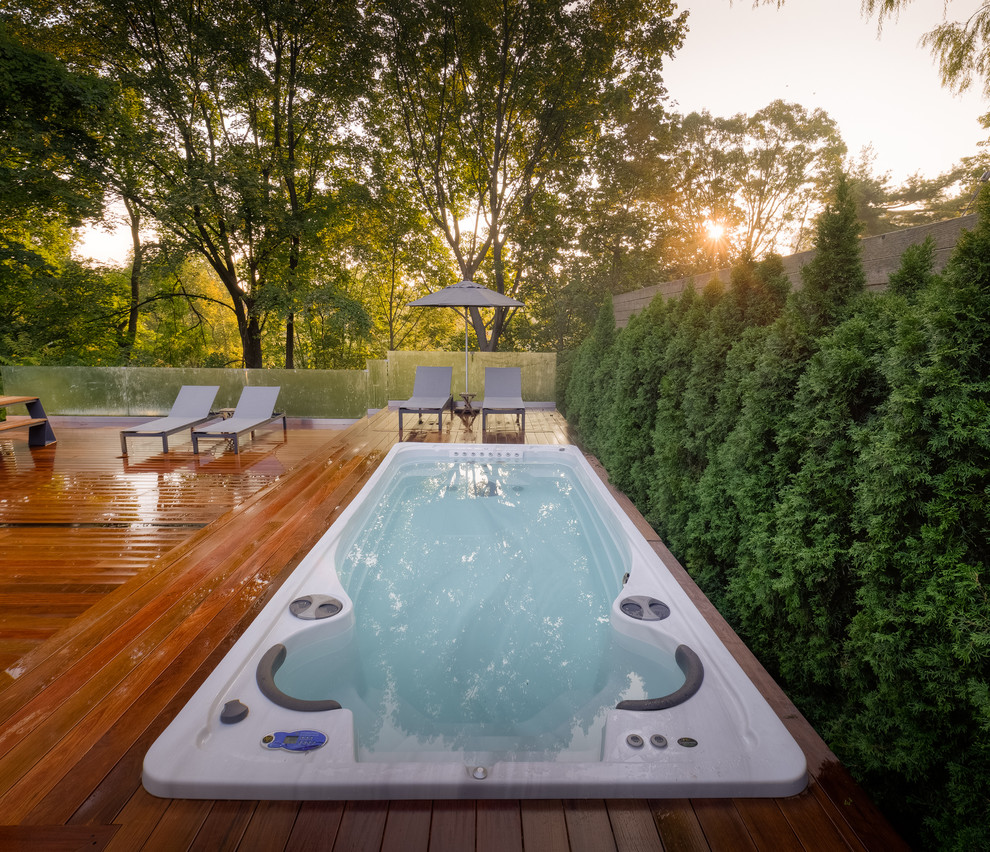 Exemple d'une piscine hors-sol et arrière tendance de taille moyenne et rectangle avec un bain bouillonnant et une terrasse en bois.