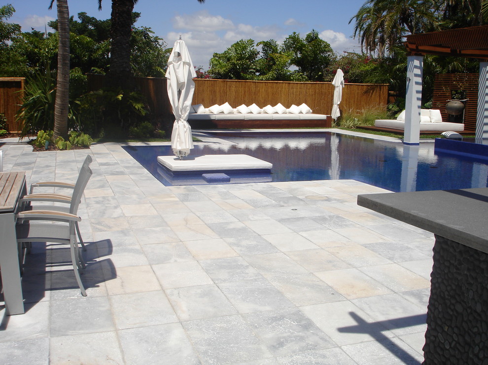 Foto di una piscina tropicale personalizzata di medie dimensioni e dietro casa con una vasca idromassaggio e pavimentazioni in mattoni