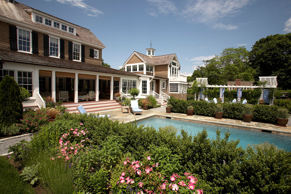 This is an example of a classic back rectangular swimming pool in New York with natural stone paving.