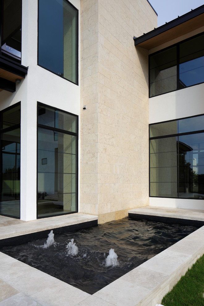 Foto di una piscina monocorsia moderna rettangolare di medie dimensioni e dietro casa con fontane e piastrelle