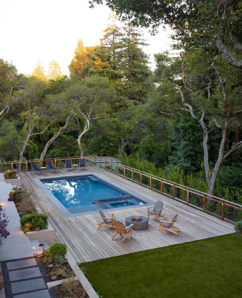 На фото: большой прямоугольный бассейн на заднем дворе в стиле модернизм с настилом с