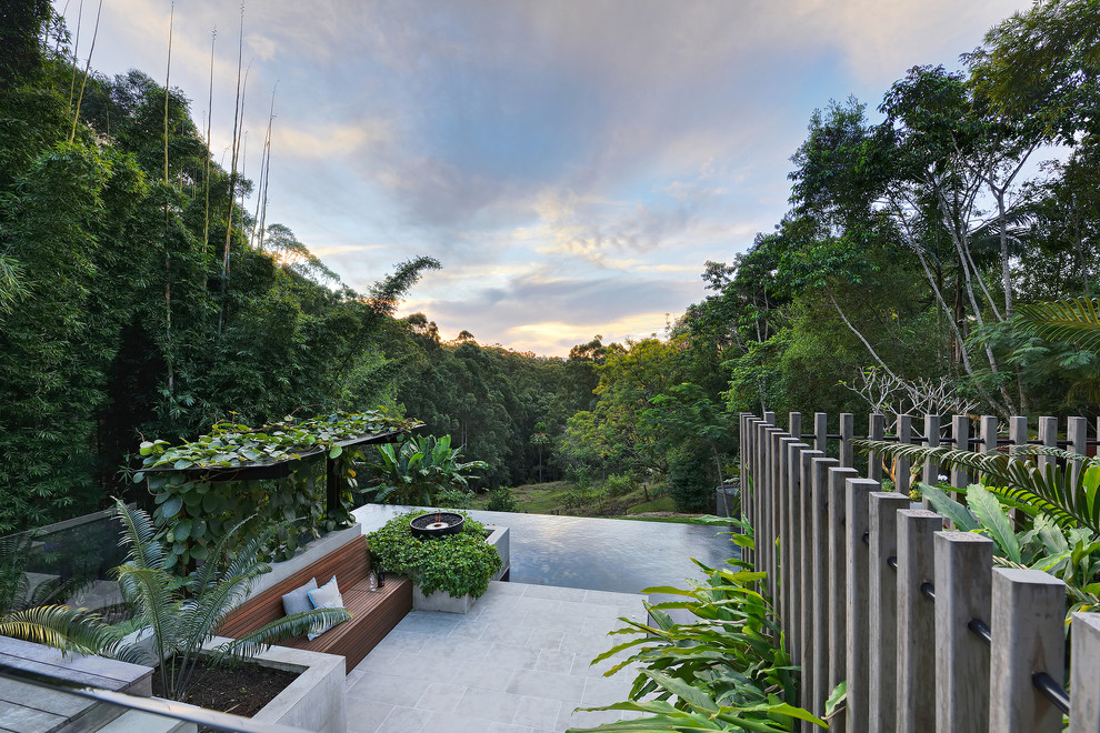 Example of a large island style backyard stone and rectangular infinity pool design in Sunshine Coast