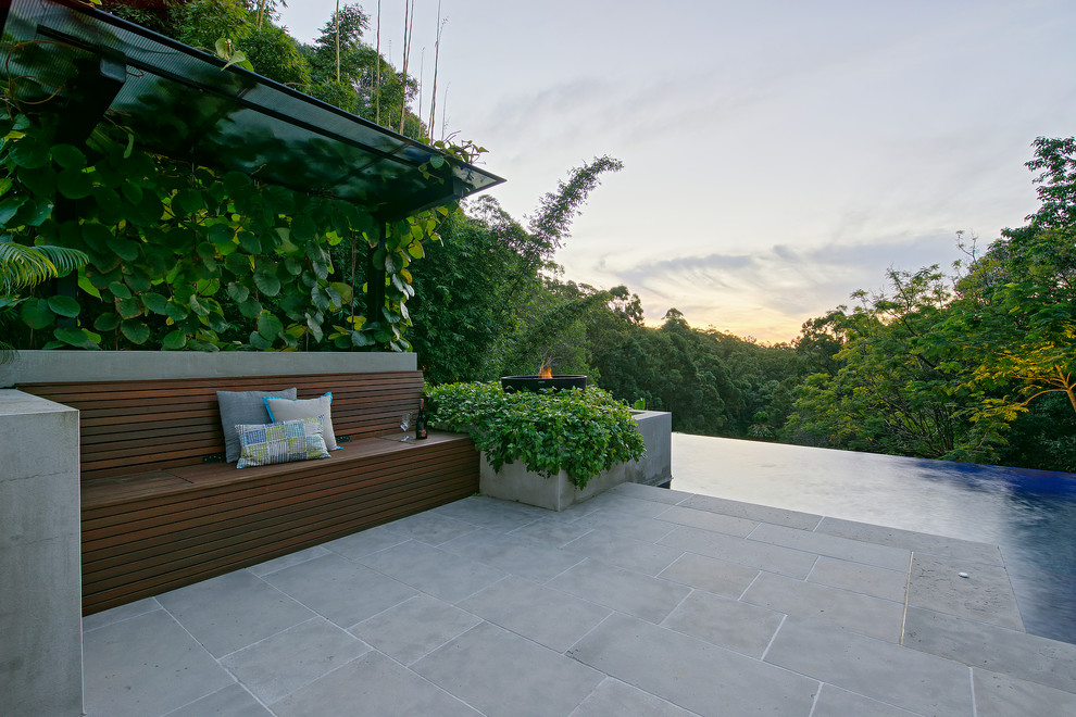 Diseño de piscina infinita tropical grande a medida en patio trasero con adoquines de piedra natural