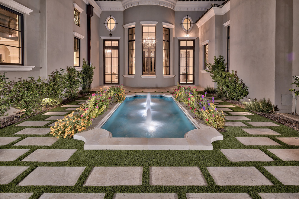 Imagen de piscina con fuente natural mediterránea grande a medida en patio trasero con adoquines de hormigón