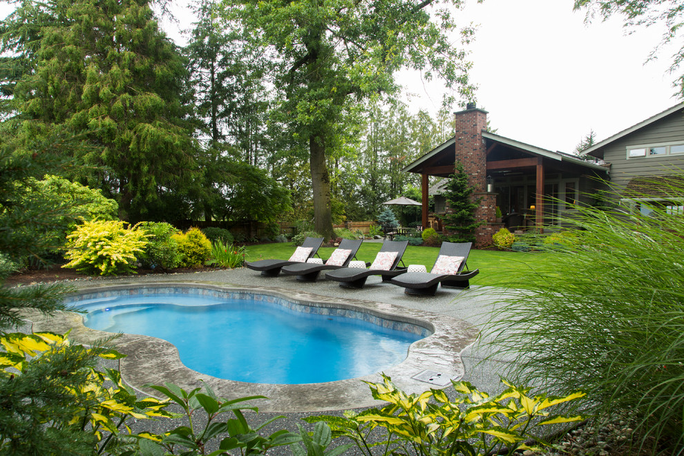 Imagen de piscina con tobogán alargada rural de tamaño medio rectangular en patio trasero con losas de hormigón