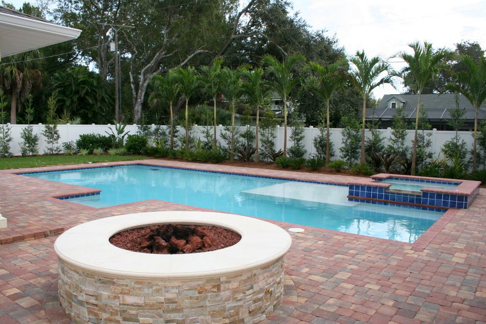 Foto på en mellanstor medelhavsstil pool på baksidan av huset, med spabad och marksten i tegel
