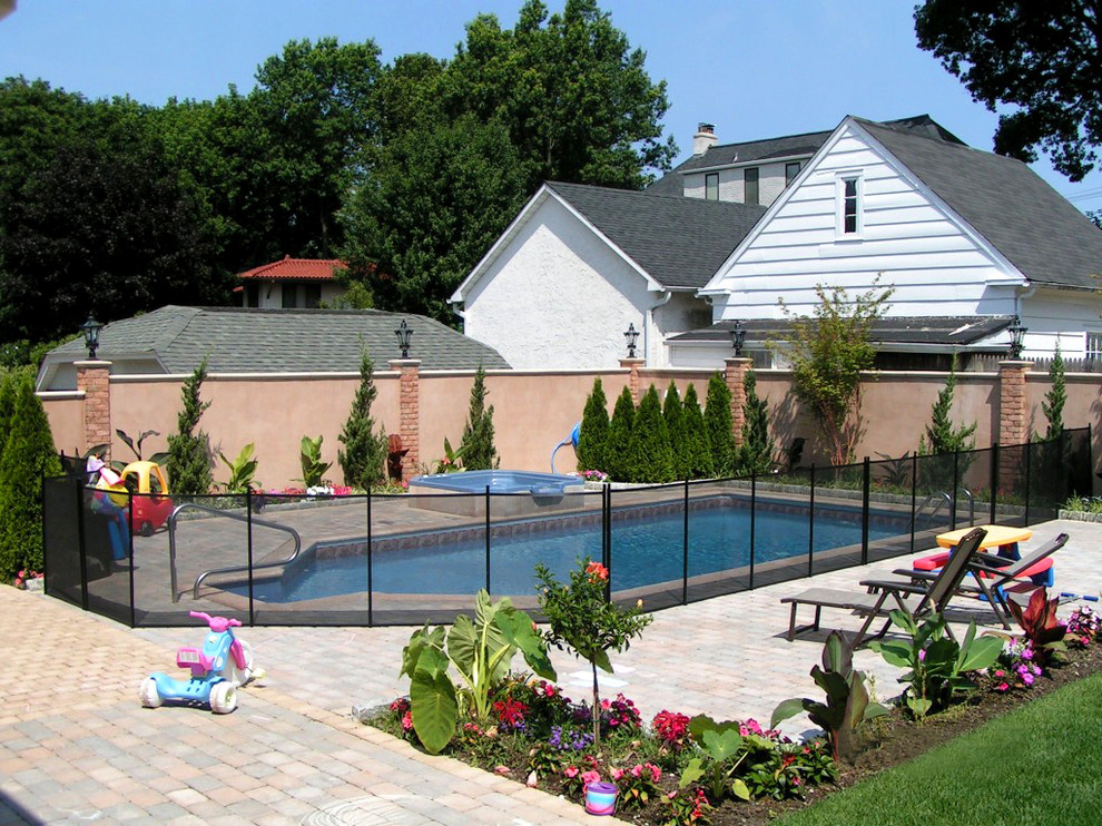 Modelo de piscina tradicional en patio trasero con adoquines de hormigón