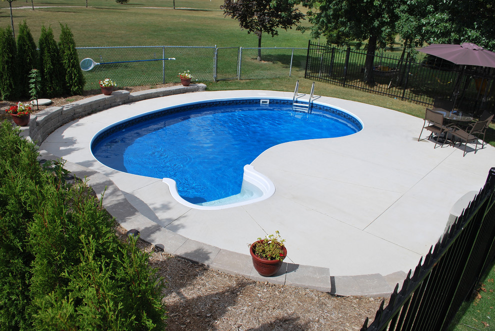 Inspiration for a mid-sized timeless backyard concrete and custom-shaped pool remodel in Toronto
