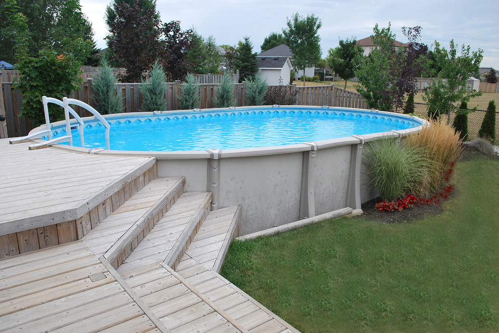 Ejemplo de piscina elevada clásica de tamaño medio redondeada en patio trasero con entablado