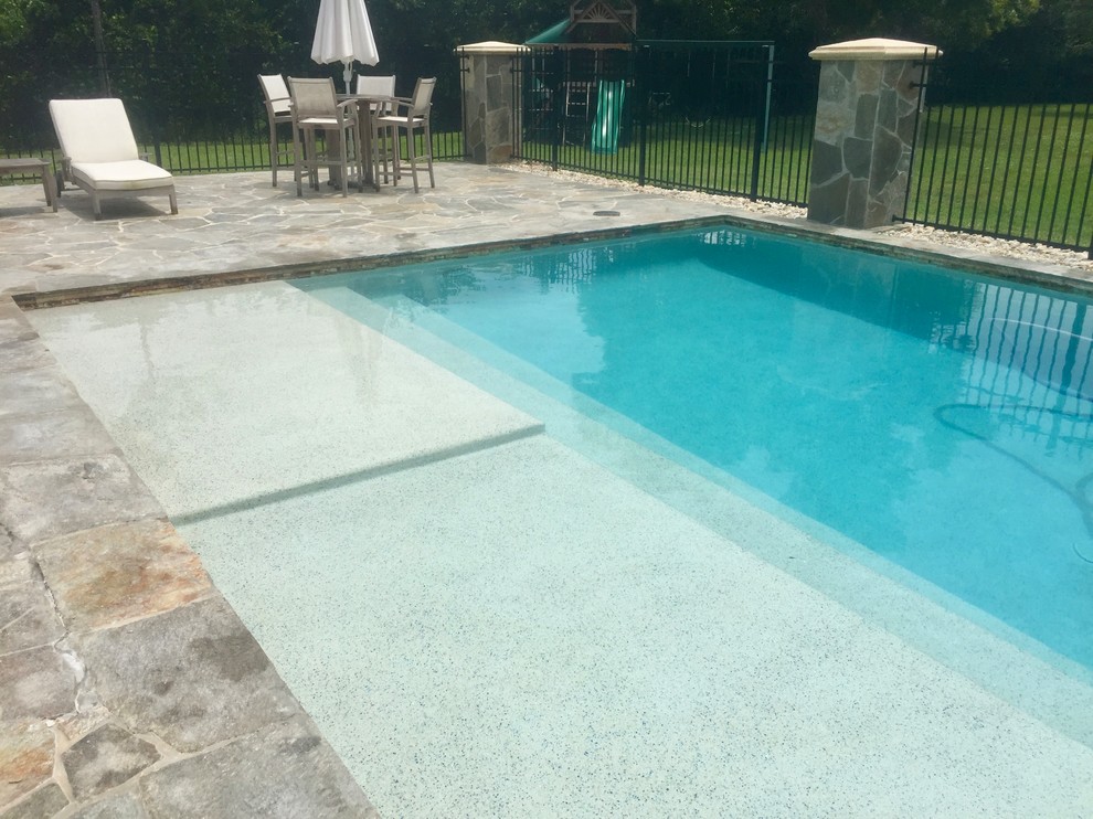 Ejemplo de piscina alargada tropical grande rectangular en patio trasero con adoquines de piedra natural