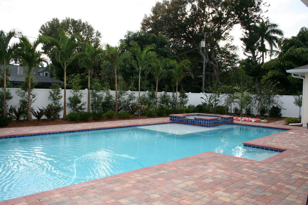 Immagine di una piscina mediterranea rettangolare di medie dimensioni e dietro casa con una vasca idromassaggio e pavimentazioni in mattoni