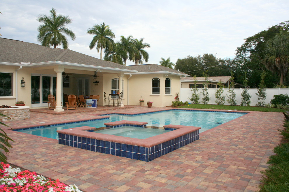 Immagine di una piscina tropicale rettangolare di medie dimensioni e dietro casa con una vasca idromassaggio e pavimentazioni in mattoni