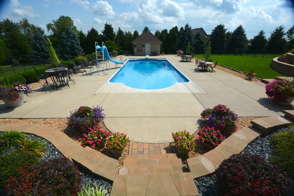 Foto på en stor funkis pool på baksidan av huset, med vattenrutschkana och betongplatta
