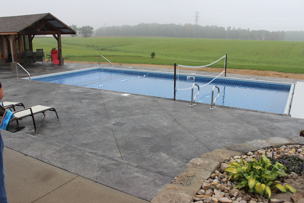 Ispirazione per una grande piscina moderna rettangolare dietro casa con una dépendance a bordo piscina e cemento stampato