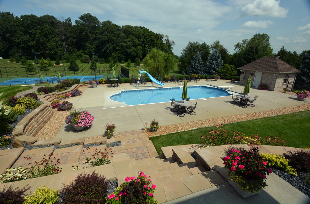 Immagine di una grande piscina minimalista rettangolare dietro casa con un acquascivolo e lastre di cemento