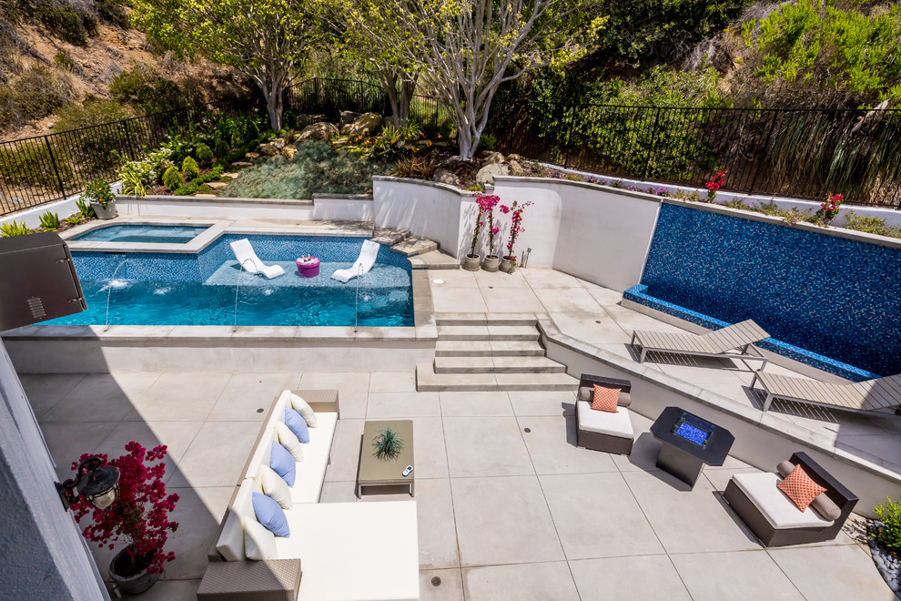 Ejemplo de piscinas y jacuzzis alargados contemporáneos de tamaño medio a medida en patio trasero con losas de hormigón