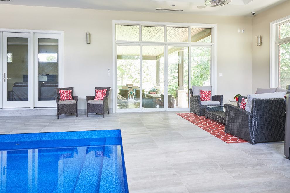 На фото: большой прямоугольный бассейн в доме в современном стиле с домиком у бассейна и покрытием из каменной брусчатки с
