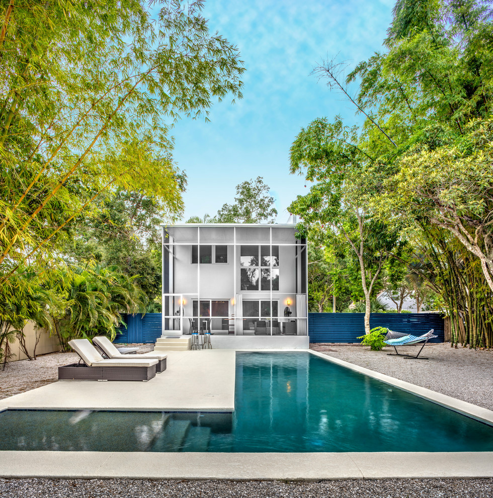 Diseño de piscina alargada contemporánea en forma de L en patio trasero con losas de hormigón
