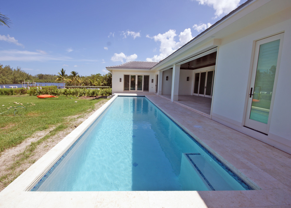 Foto di una grande piscina monocorsia tropicale rettangolare dietro casa con pavimentazioni in pietra naturale