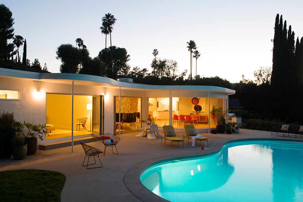 Pool house - large modern backyard concrete and kidney-shaped pool house idea in Los Angeles